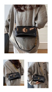 Détail du sac à bandoulière en cuir brillant noir avec fermoir doré et chaîne en métal