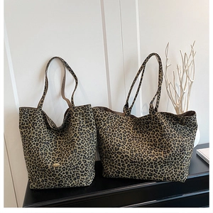 Close-up of leopard print canvas tote bags with metal logo detail and sturdy straps