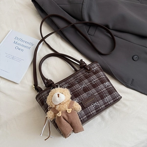 Détail du sac bandoulière à carreaux avec nœud et breloque en peluche d'ours marron
