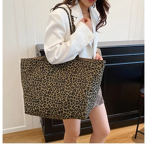Detailed view of large leopard print tote bag worn on shoulder by model in a white suit