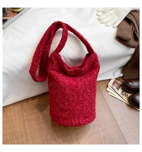 Gros plan du sac seau rouge en tissu bouclé avec accessoires d'hiver et texture laine