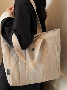 Large off-white nylon tote bag with wide strap and brand label for commute use