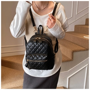 Détail du mini sac à dos noir matelassé avec motif losanges et fermetures éclair dorées