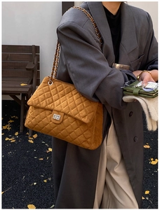 Détail du sac en daim matelassé beige avec surpiqûres en losange et fermoir en métal
