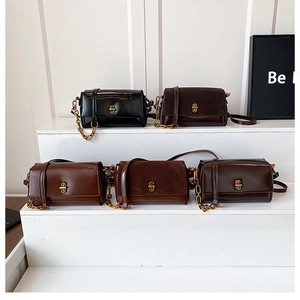Détail de sacs trapézoïdaux élégants avec fermoirs dorés et bandoulières en cuir et chaîne