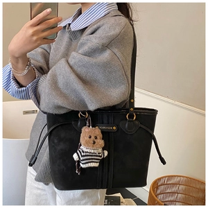 Vue détaillée du grand sac cabas noir avec pendentif ours rayé et cordon de serrage latéral