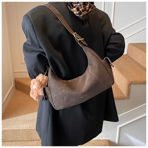 Detail view of dark brown faux suede shoulder bag with gold hardware and plush bear charm