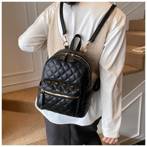 Détail d'un mini sac à dos noir matelassé chic avec fermetures éclair dorées sur modèle