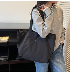 Vue détaillée du grand sac cabas noir en nylon avec logo CM porté par un mannequin en salle