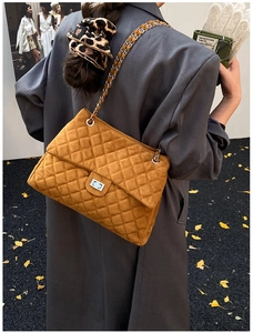 Détail du sac cabas matelassé orange avec chaîne et serrure sur un manteau en laine