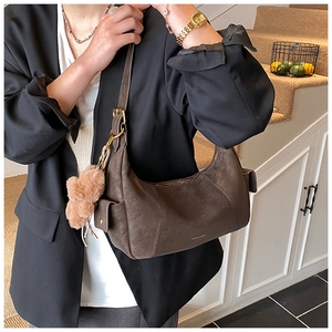Detail of dark brown faux suede hobo bag with a plush bear charm and golden buckle