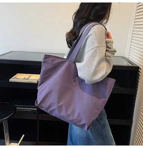 Vue latérale du grand sac fourre-tout en nylon violet avec badge en métal et bandoulière large