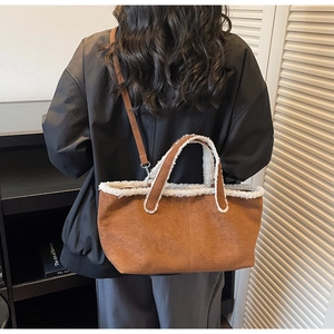 Detail of a brown suede tote bag with white lamb wool trim shown on a person's shoulder
