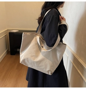 Vue détaillée d'un grand cabas en toile beige avec une fermeture à bouton minimaliste