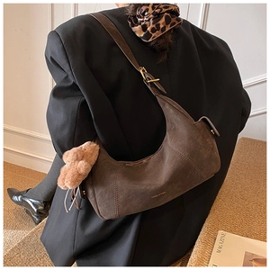 Detail of dark brown suede crescent bag with wide shoulder strap and gold buckle