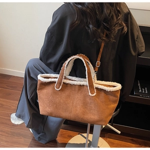 Detail view of brown suede underarm bag with white faux shearling trim and shoulder strap