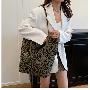 Detailed view of leopard print canvas tote bag with brown straps styled on a model