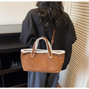 Detail of brown suede shoulder bag with white faux fur trim and adjustable crossbody strap