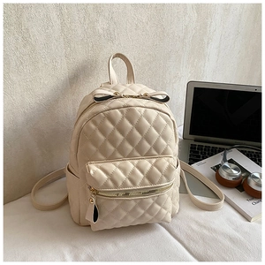 Détail d'un sac à dos matelassé crème avec nœud noir et tirettes de fermeture en cuir