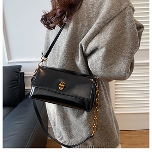Détail du sac rectangulaire en cuir verni noir avec fermoir doré et chaîne luxe