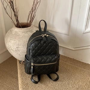 Gros plan d'un mini sac à dos matelassé noir avec des fermetures éclair dorées chic