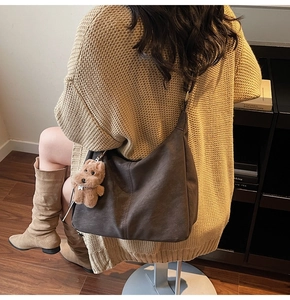 Détail du grand sac cabas taupe avec un porte-clé chien peluche sur un cardigan