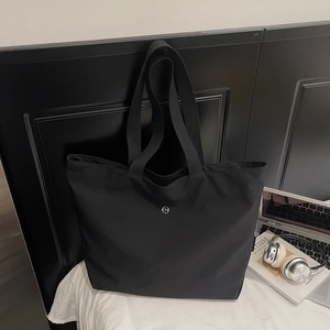 Détail du sac cabas en nylon noir avec logo CM en métal dans un bureau minimaliste