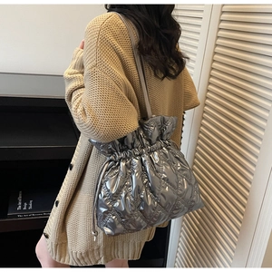 Close-up of metallic silver quilted shoulder bag with drawstring closure and diamond pattern
