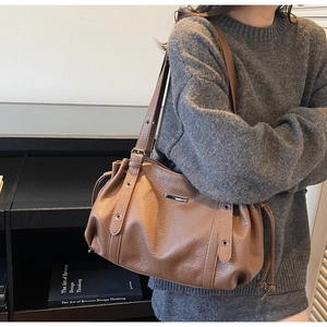 Detail of brown lychee leather tote bag with drawstring side and metal eyelet strap