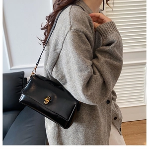 Détail d'un sac à bandoulière noir chic avec fermoir doré porté par un mannequin élégant