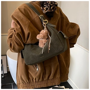 Detail of olive green suede crescent bag with adjustable buckle and brown bear charm