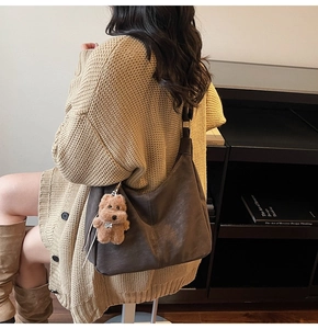 Détail d'un grand sac Hobo marron foncé avec un joli pendentif chiot en peluche
