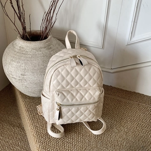 Détails du mini sac à dos matelassé beige avec fermetures éclair dorées et élégantes