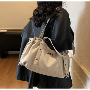 Close-up of cream pleated tote bag showing lychee pattern leather and metallic buckle