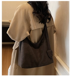Detail view of a large vintage coffee brown suede tote bag worn over a trench coat