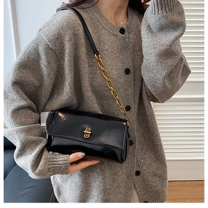 Détail du sac bandoulière en cuir verni noir avec fermoir doré et bandoulière chaîne
