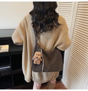 Détail d'un sac cabas en daim gris avec breloque d'ours en peluche et franges de mode
