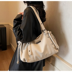 Detail of cream oversized hobo bag showing litchi grain texture and metal eyelet accents
