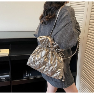 Close-up of metallic quilted drawstring bucket bag styled on a gray sweater