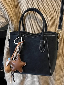 Minimalistische schwarze Beuteltasche mit Kontrastnähten und Sternanhänger für Wintermode