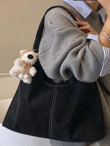 Minimalist black tote bag with white stitching and plush bear charm for daily commuting
