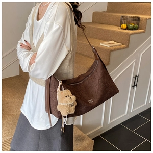 Deep brown pleated Hobo bag with gold logo and cute plush bear charm on model shoulder