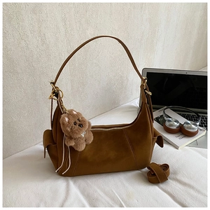 Caramel suede shoulder bag with adjustable strap and cute plush bear charm detail