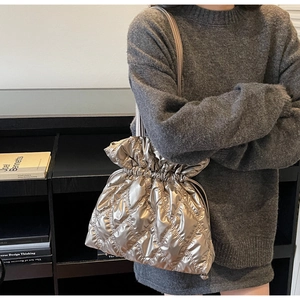 Detail of silver quilted nylon bucket bag with drawstring closure and chain strap