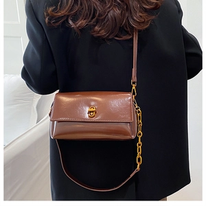 Détail du sac à bandoulière vintage marron avec fermoir tournant doré et chaîne