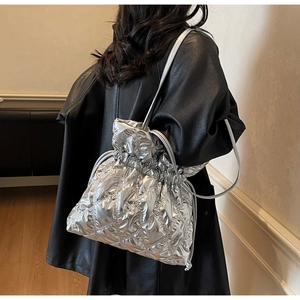 Detailed view of silver quilted drawstring bucket bag with metallic finish on person