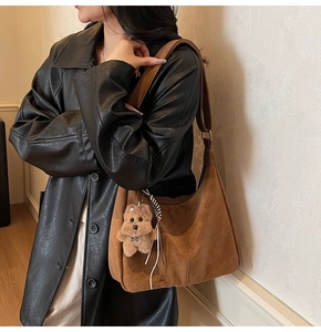 Détail d'un grand sac cabas marron en daim avec un pendentif chiot et ruban sur mannequin