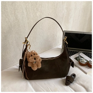 Detail view of coffee brown suede tote bag with brand logo and cute plush dog pendant