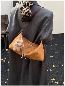 Detailed view of brown wrinkled leather shoulder bag with cute plush bear pendant accessory