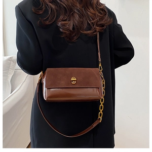 Détail du sac à bandoulière marron avec fermoir doré et bandoulière en chaîne